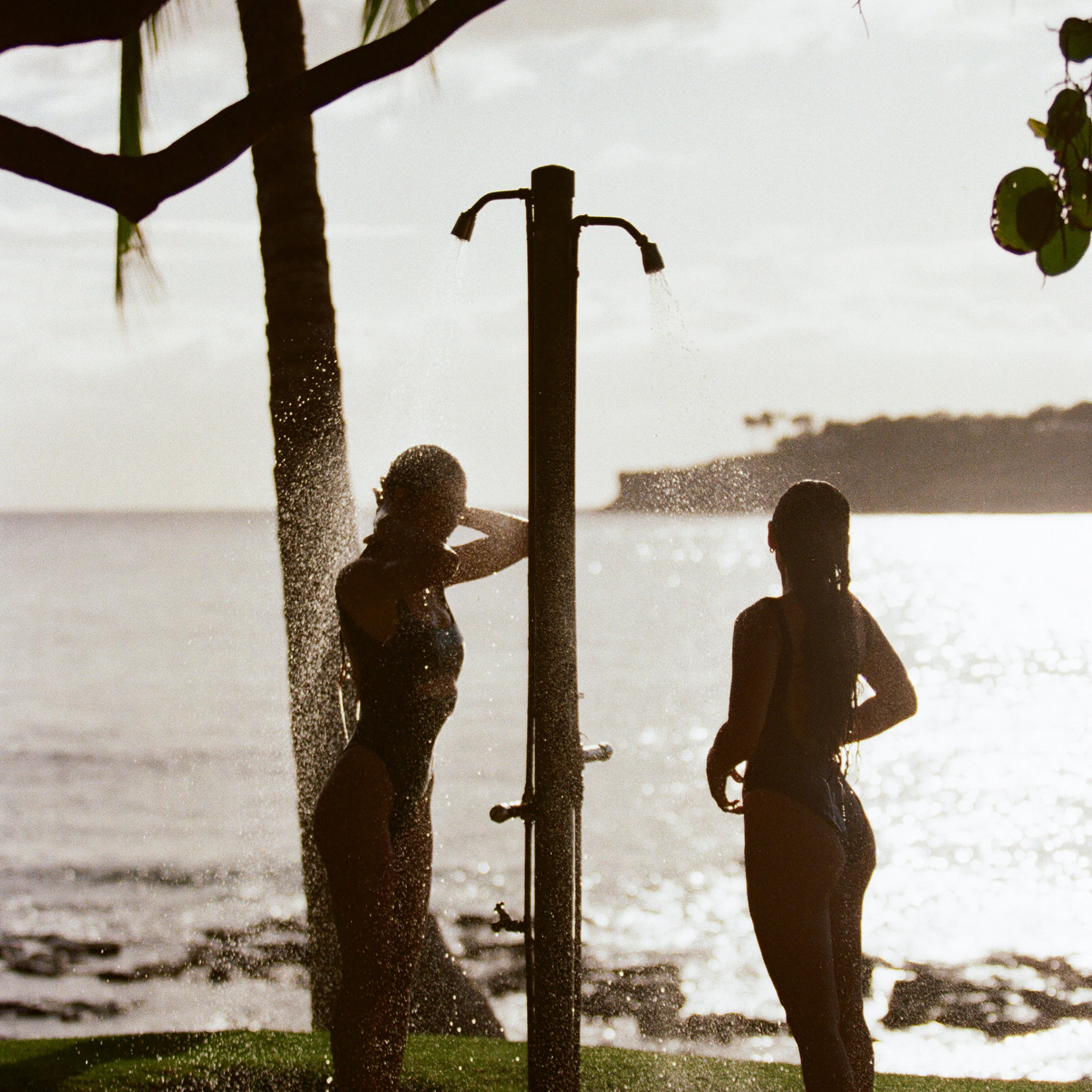 girls rinsing off in the shower by the beach