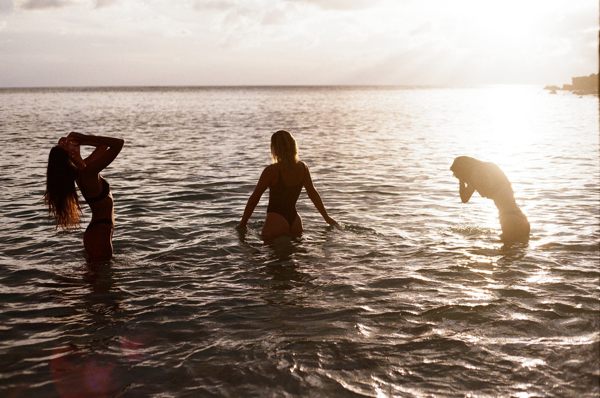 Three girls in the ocean at sunset