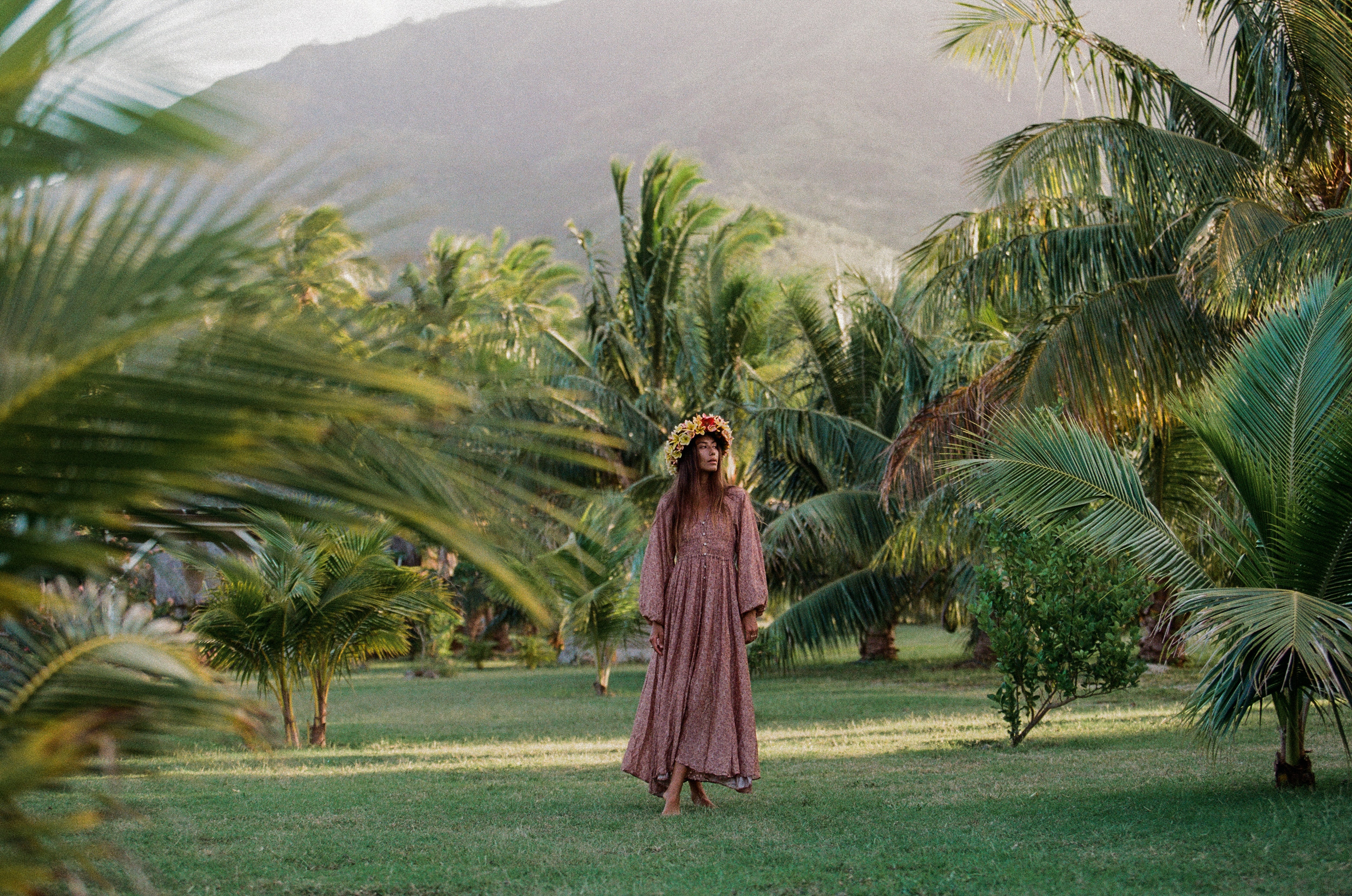 Girl in a long red dress with palm trees surrounding her