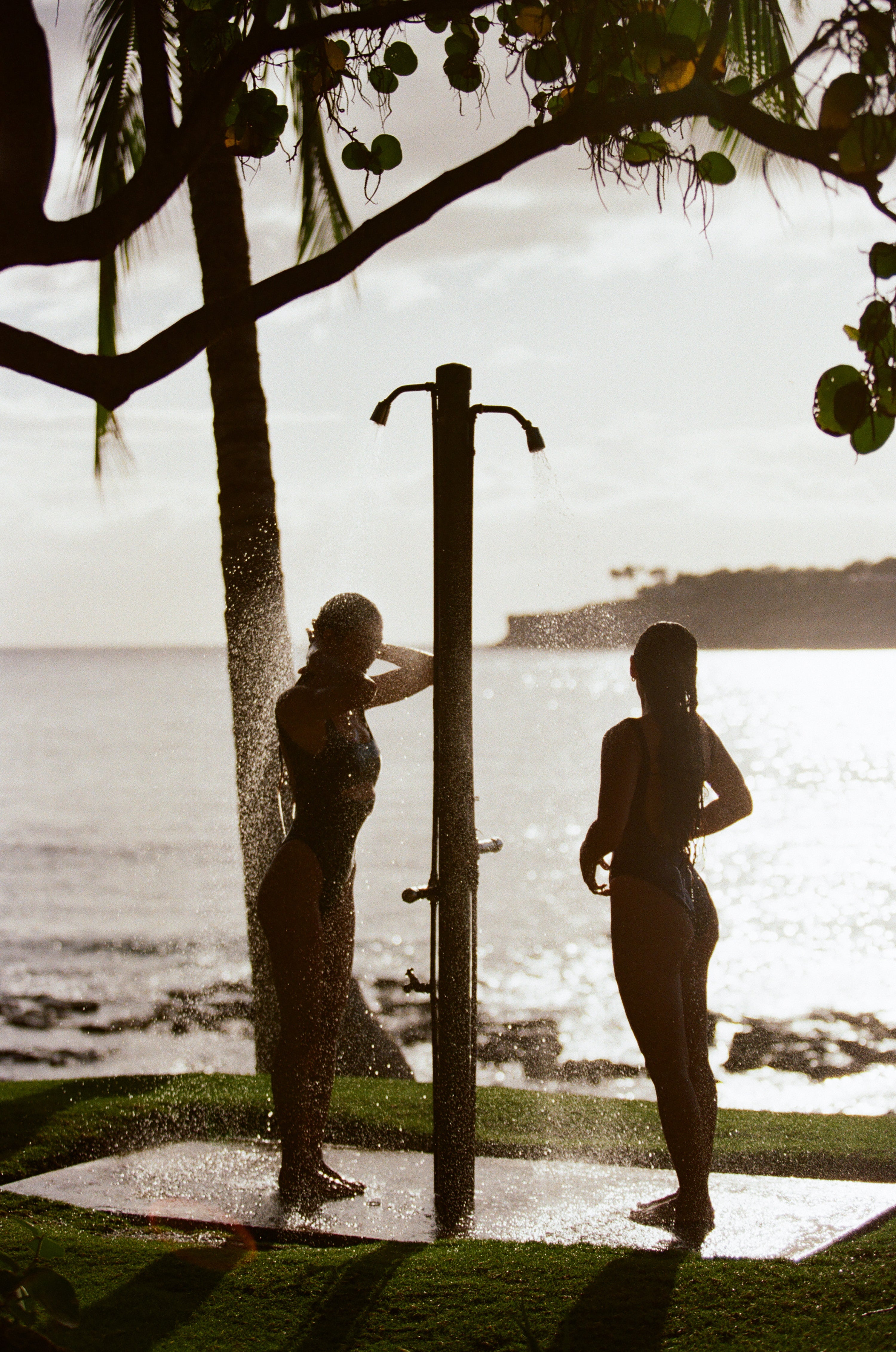 two girls rinsing off by the beach at sunset