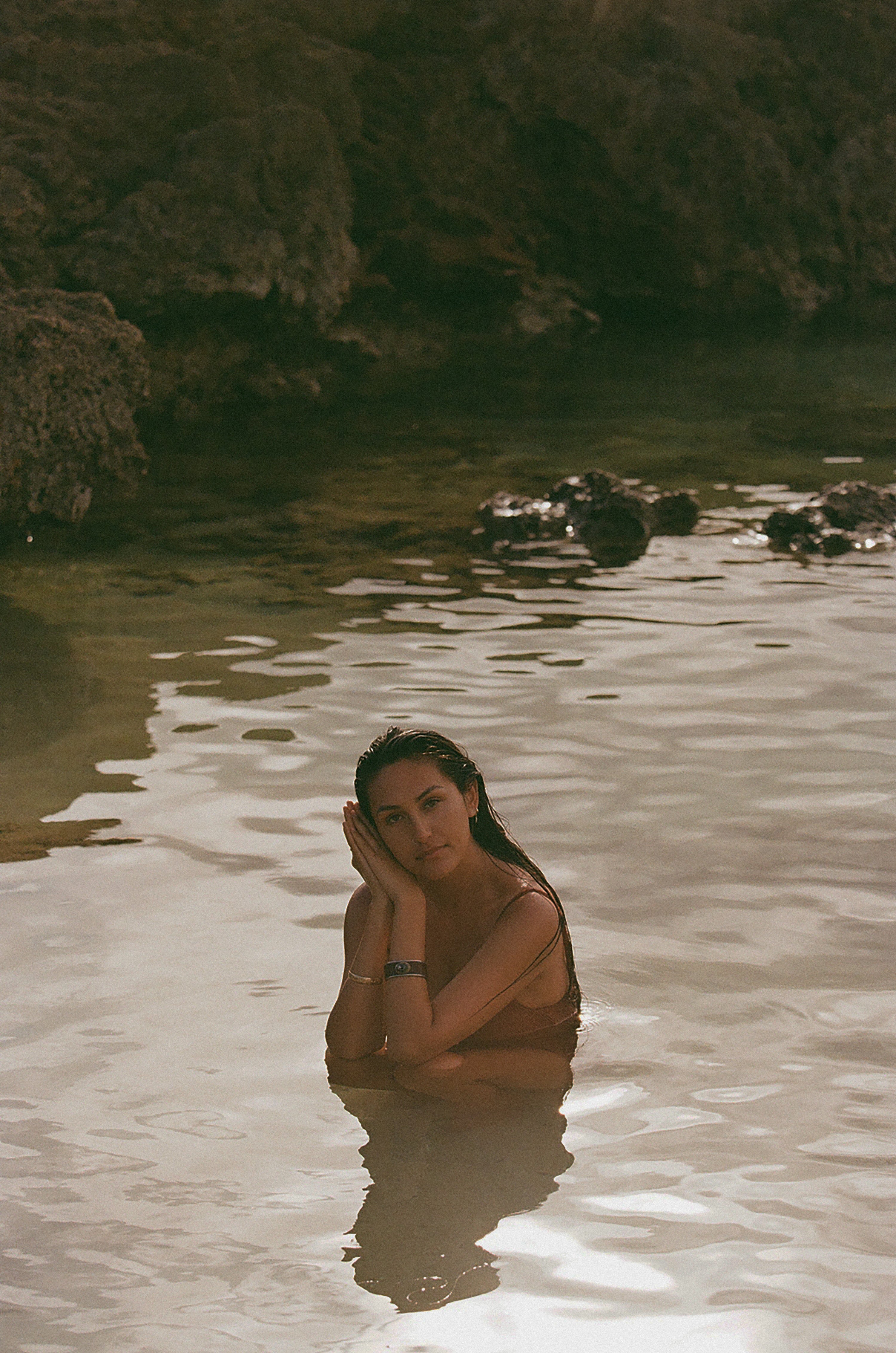 girl in tide pool in rust one piece bikini