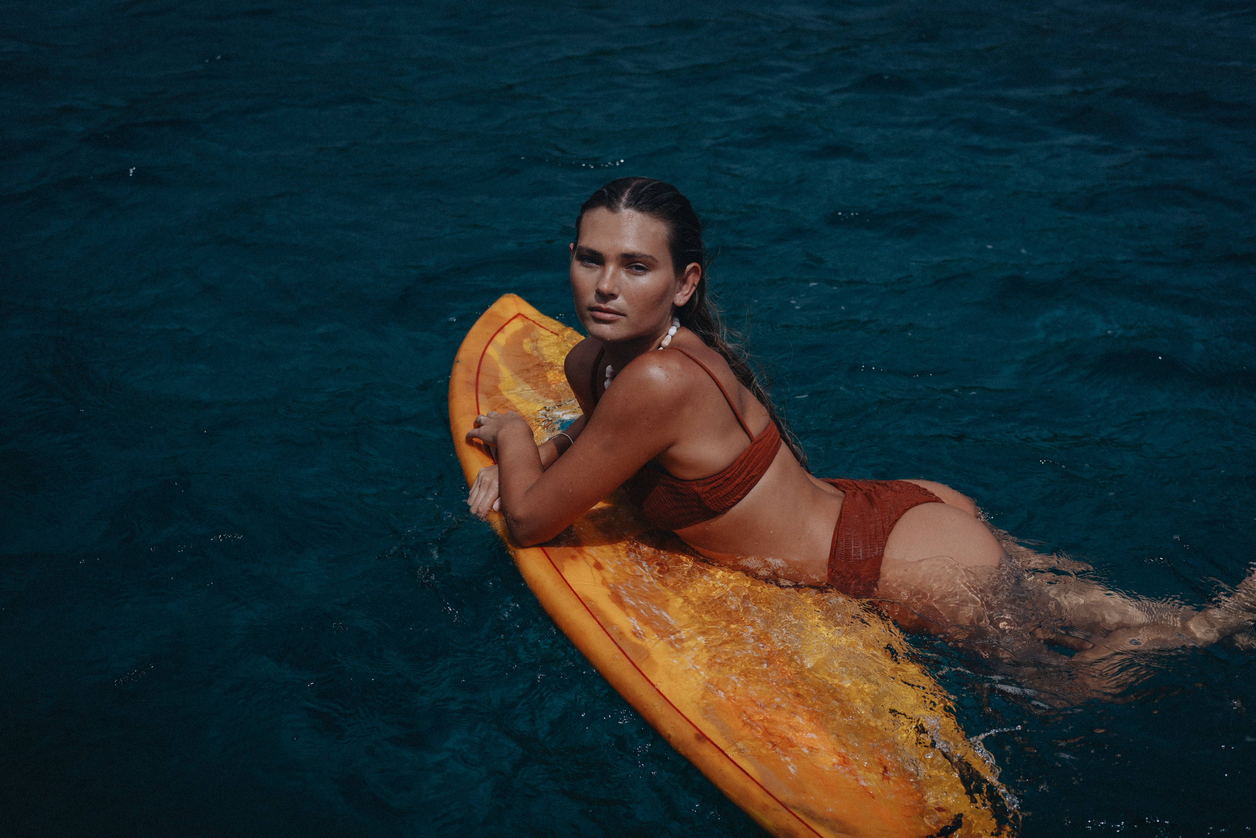 girls laying on surf board in water