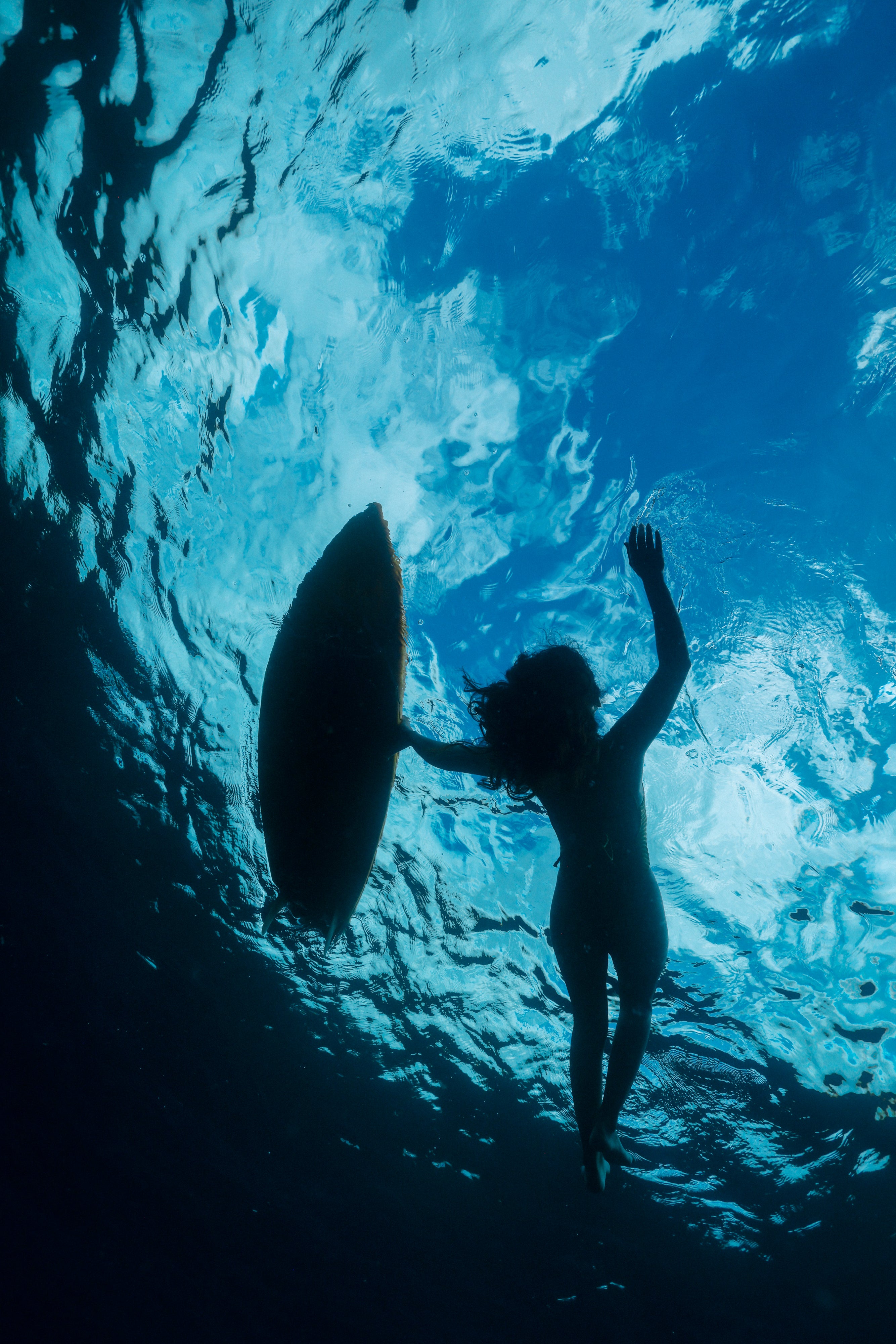 underwater shot of a girl laying in the water with a shortboard