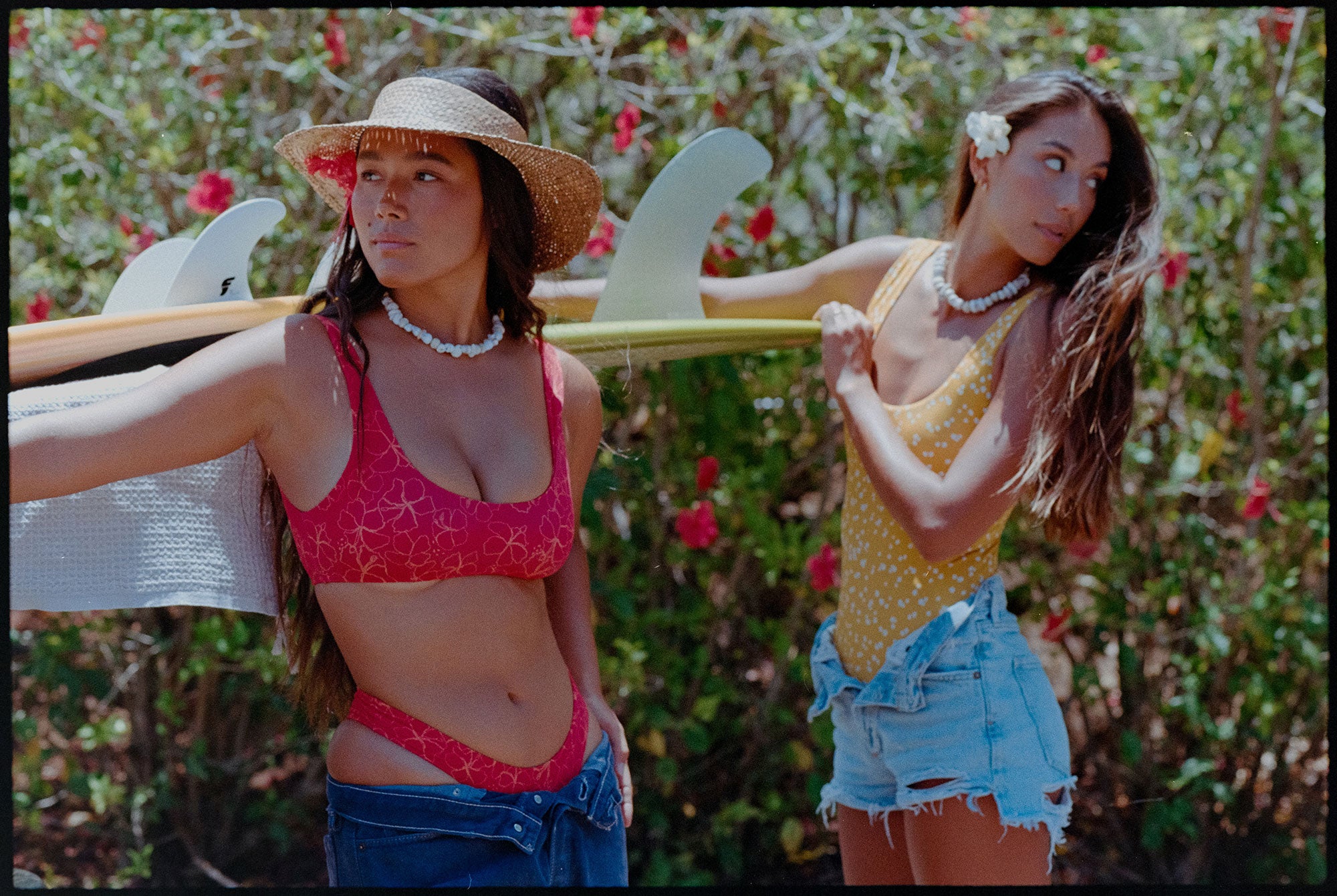 Two girls holding longboards with flowers in their hair