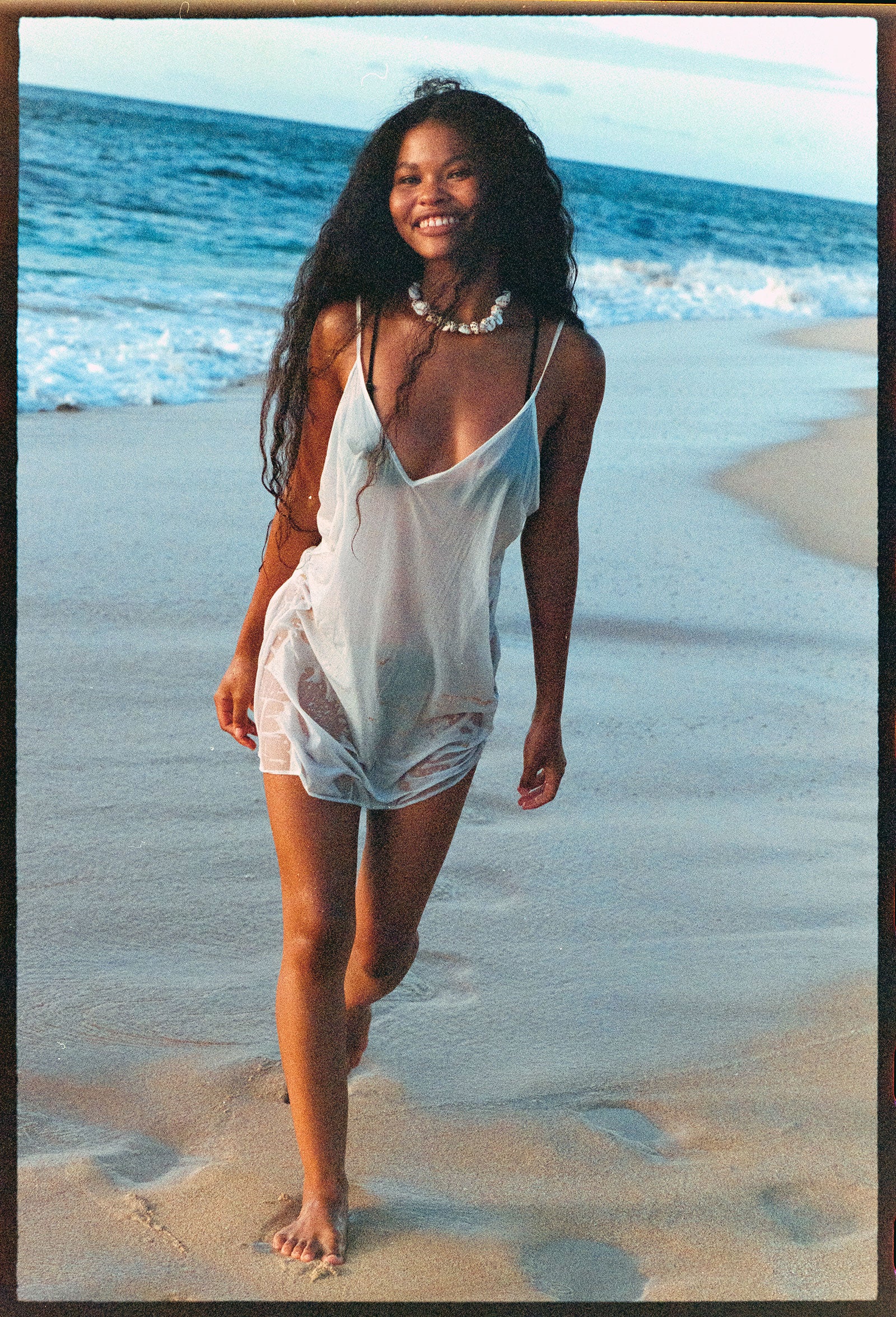 Girl walking on the beach with a white tank dress